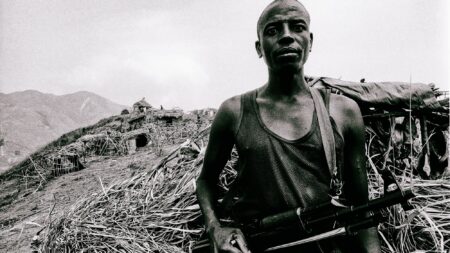 A survivor of the Rwandan genocide and a soldier of the Forces for the Democratic Liberation of Rwanda stands guard during "peace negotiations" with the United Nations in the eastern Congo. Photo by Keith Harmon Snow